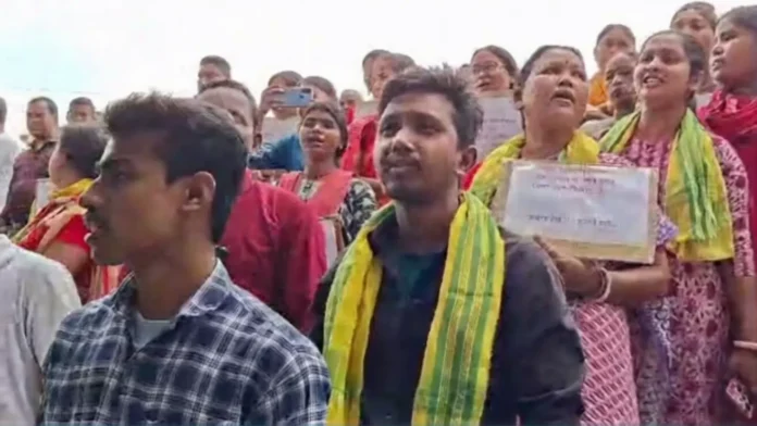 Protesters gather outside the alleged shop in Siliguri’s Ward 42, raising slogans and demanding its closure over claims of illegal liquor sales. Sunday, 22 March 2026.