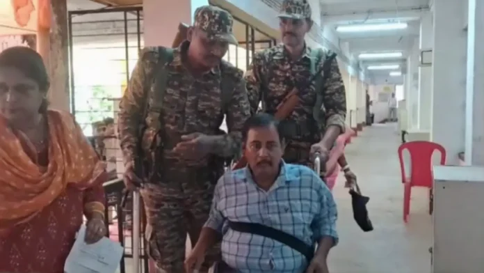 CAPF personnel assist an ailing voter on a wheelchair to reach a polling booth in Jalpaiguri, ensuring he is able to cast his vote. Thurday, 23 April 2026.
